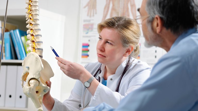 Arzt erklärt Patient mögliche Komplikationen einer metabolischen Knochenerkrankung aufgrund von CNK