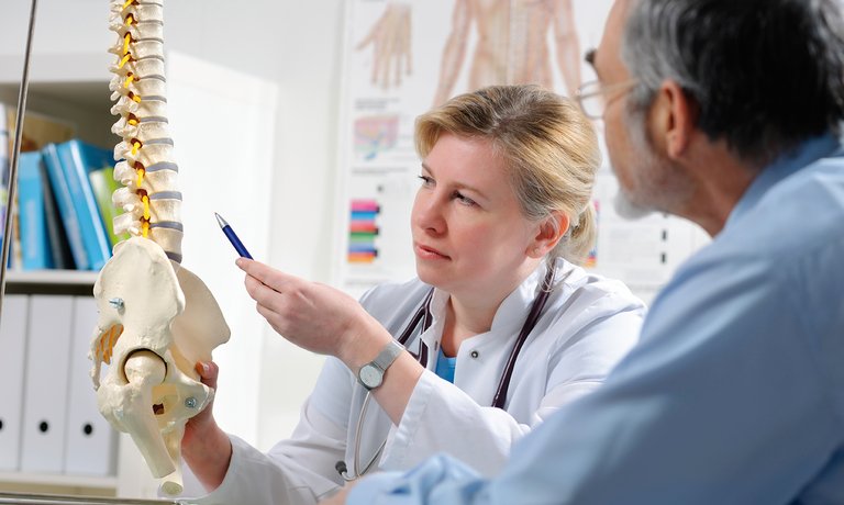 Arzt erklärt Patient mögliche Komplikationen einer metabolischen Knochenerkrankung aufgrund von CNK